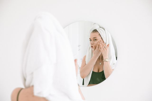 woman looking at face in the mirror
